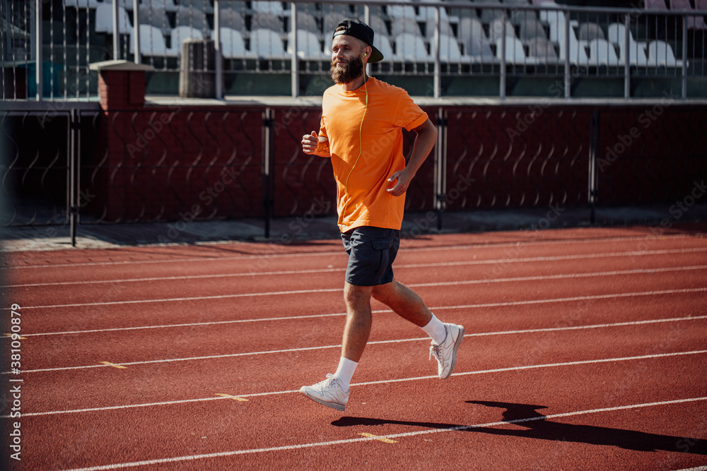Healthy lifestyle. Handsome male athlete with long beard running while listening to music using earphones.