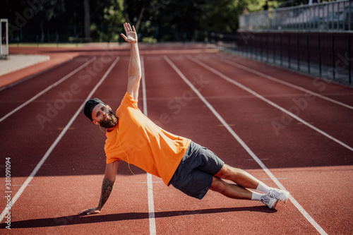 Healthy lifestyle. Handsome caucasian male athlete with long beard doing strength exercises in the stadium for cardio workout © San4ezz007