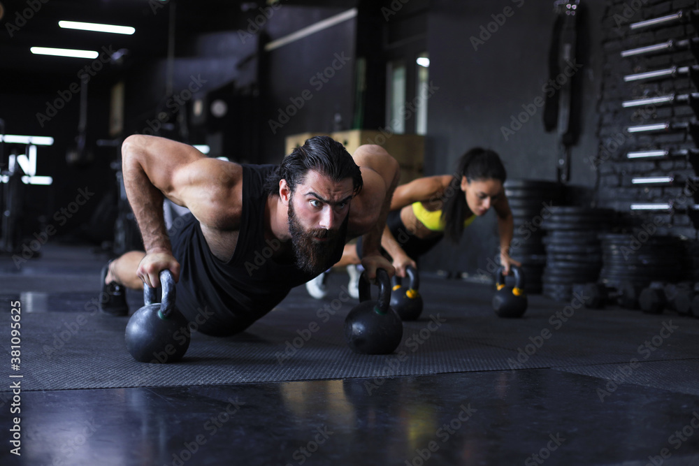 Obraz premium Sporty man and woman doing push-up in a gym.
