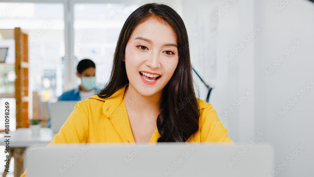 Asia businesswoman social distancing in new normal situation for virus prevention while using laptop presentation to colleagues about plan in video call while work in office. Life after corona virus. Asia businesswoman social distancing in new normal situation for virus prevention while using laptop presentation to colleagues about plan in video call while work in office. Life after corona virus.