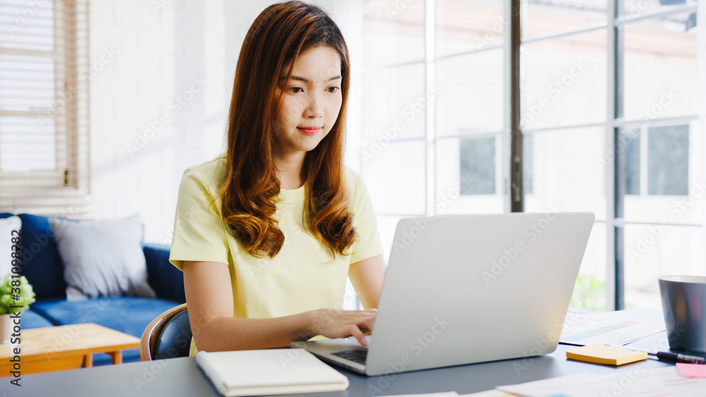 Asia businesswoman using laptop talk to colleagues about plan in video call while smart working from home at living room. Self-isolation, social distancing, quarantine for corona virus prevention. Asia businesswoman using laptop talk to colleagues about plan in video call while smart working from home at living room. Self-isolation, social distancing, quarantine for corona virus prevention.