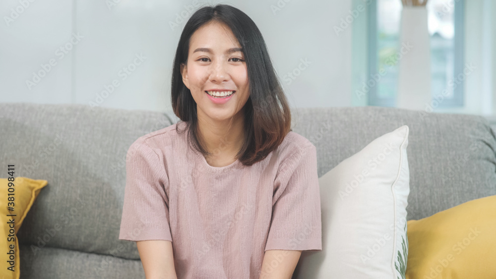 Teenager Asian woman feeling happy smiling and looking to camera while relax in living room at home. Lifestyle beautiful Asian young female using relax time at home concept. Teenager Asian woman feeling happy smiling and looking to camera while relax in living room at home. Lifestyle beautiful Asian young female using relax time at home concept.