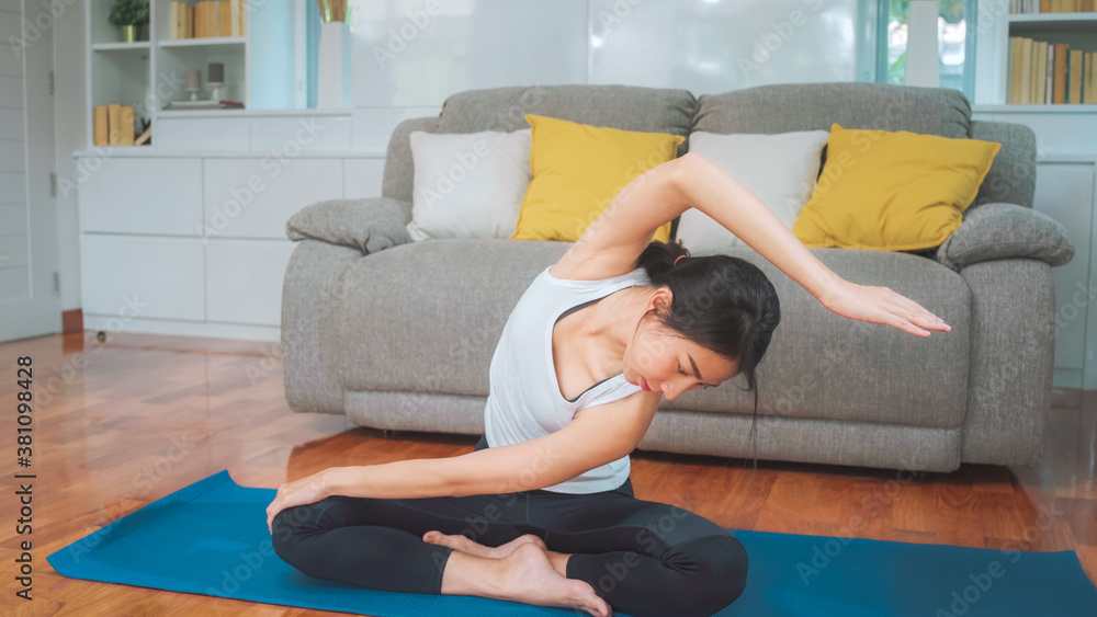 Young Asian woman practicing yoga in living room. Attractive beautiful female working out for healthy at home. Lifestyle woman exercise concept.