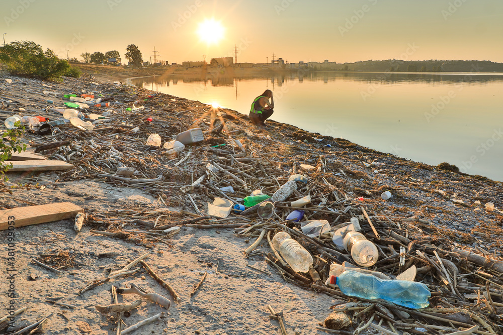 Landscape of polluted with plastic garbage shore of the lake on the sunset Landscape of polluted with plastic garbage shore of the lake on the sunset