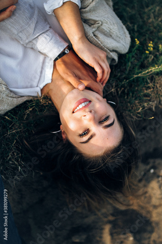 Close-up portrait of a beautiful girl lying on the ground. Man's hand touches the girl. Hand in hand. Hold hands