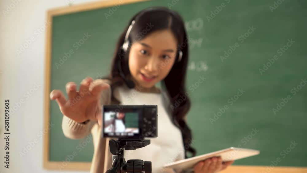 Young woman setting up video camera for online tutoring, technology, remote learning, online education. Asian school teacher preparing to deliver online course Young woman setting up video camera for online tutoring, technology, remote learning, online education. Asian school teacher preparing to deliver online course