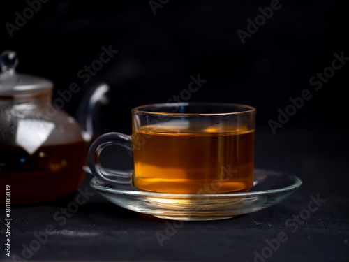 A cup of freshly brewed hot tea and a teapot on the table