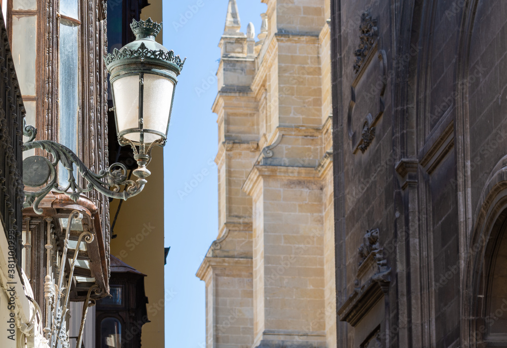 Detail of a lamppost illuminated by the morning sun in a narrow street next to the cathedral of Granada