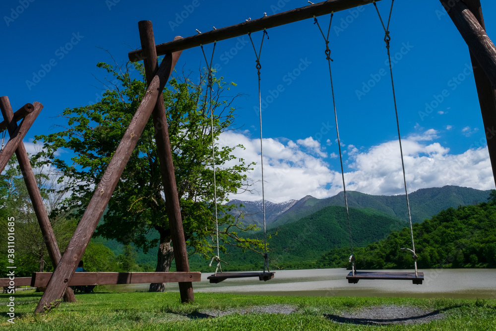 Swing in the park against of mountains and lake. Selective focus Swing in the park against of mountains and lake. Selective focus
