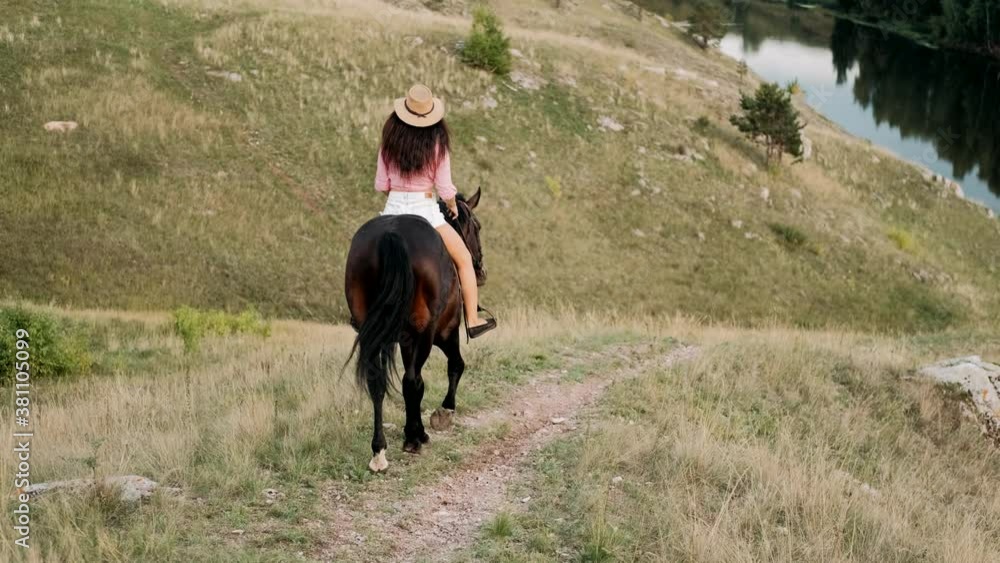 Beautiful girl in hat riding a horse among the hills. Female rider rides a graceful horse. Horseback riding. Love and friendship concept. Beautiful girl in hat riding a horse among the hills. Female rider rides a graceful horse. Horseback riding. Love and friendship concept.