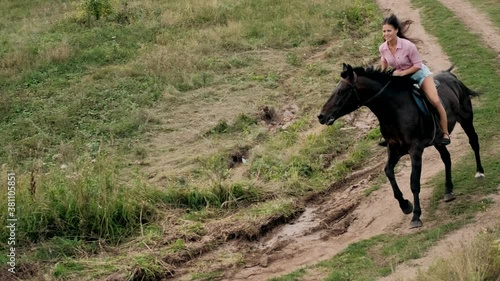 Woman horseback riding, galloping down road on beautiful brown horse in cinematic slow motion. Horseback riding. Love and friendship concept.