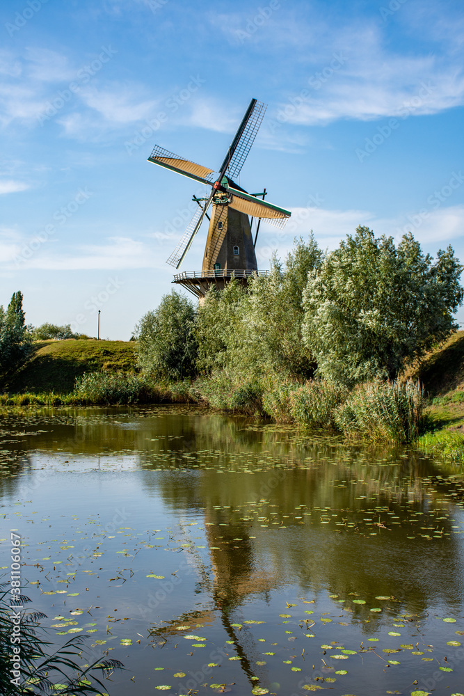 Flour windmill  'Nooit gedagt' on the waterfront of the fortified town of Woudrichem in summer in the Netherlands