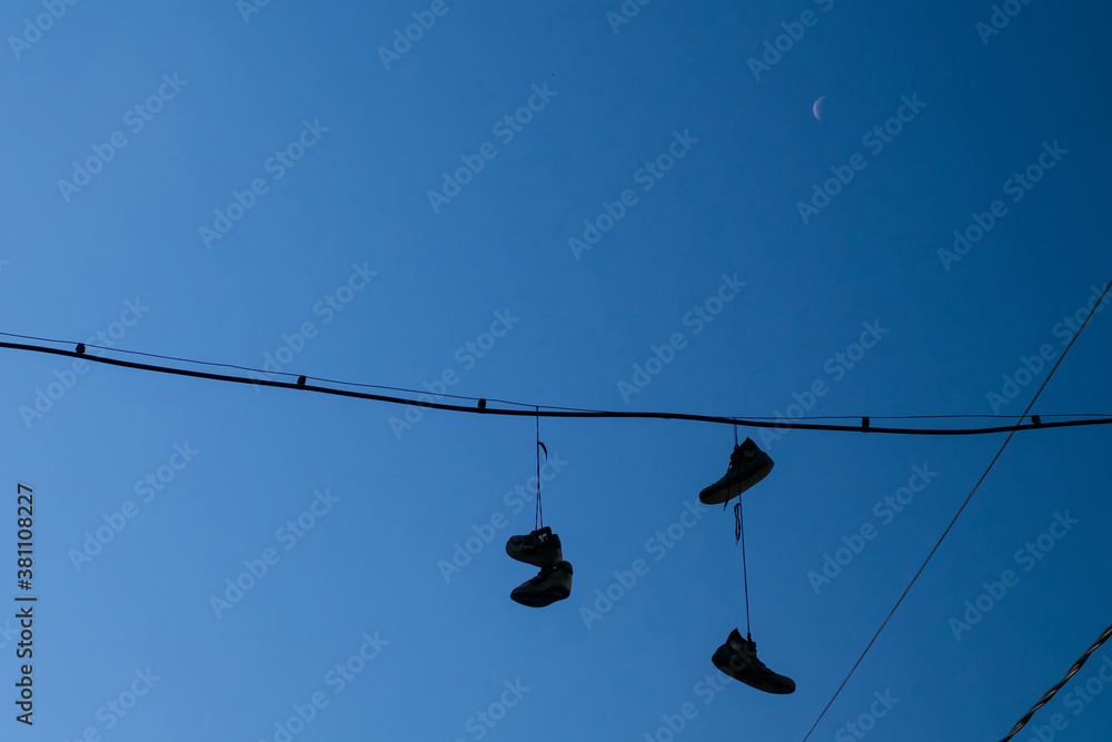 Silhouettes of shoes hanging on wires against the blue sky. Selective focus Silhouettes of shoes hanging on wires against the blue sky. Selective focus