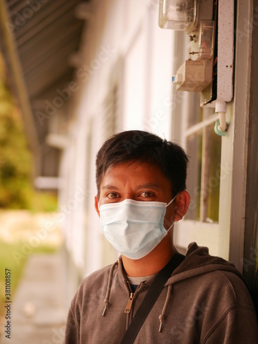 Protrait of an Indonesian young man using a medical mask during the Covid-19 pandemic. Handsome Indonesian guy wears a surgical mask to protect himself from coronavirus
