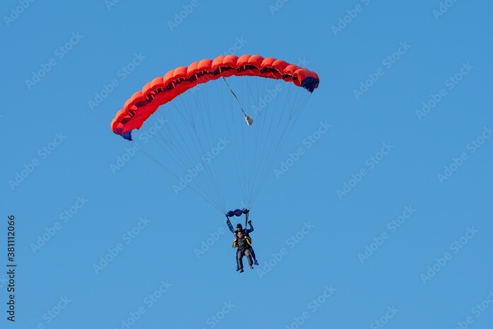 Tandem parachute jump. Silhouette of skydiver flying in blue clear sky. Concepts of extreme sport and adrenaline. Tandem parachute jump. Silhouette of skydiver flying in blue clear sky. Concepts of extreme sport and adrenaline.