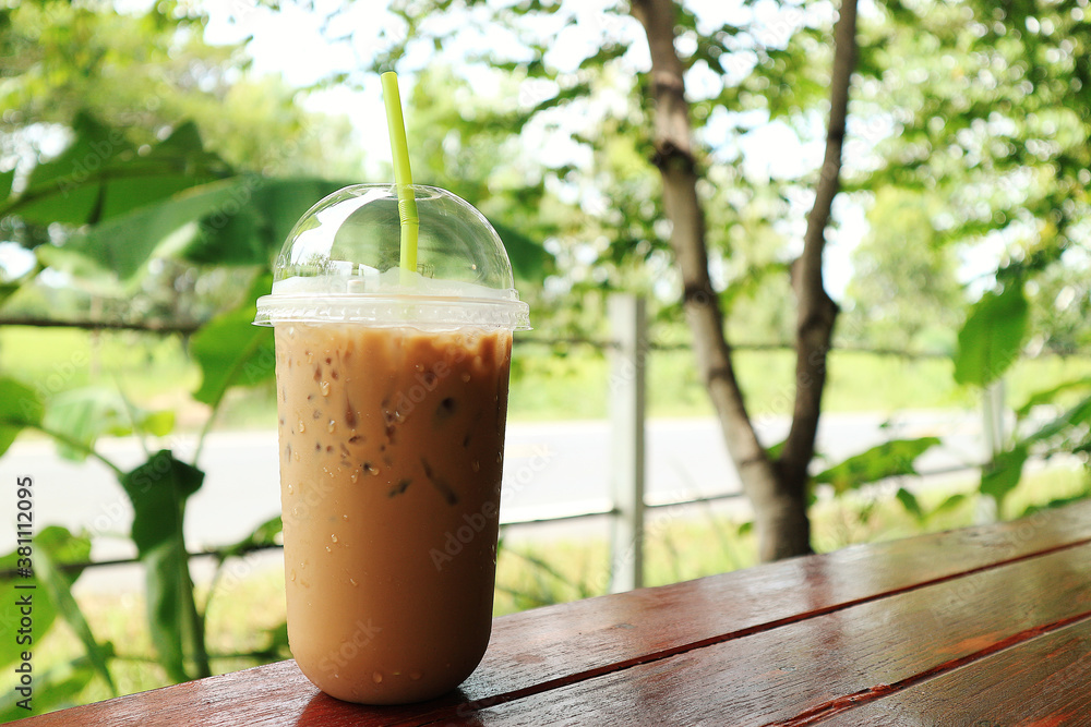 Iced coffee in plastic mug on wood and natural background. Iced coffee in plastic mug on wood and natural background.