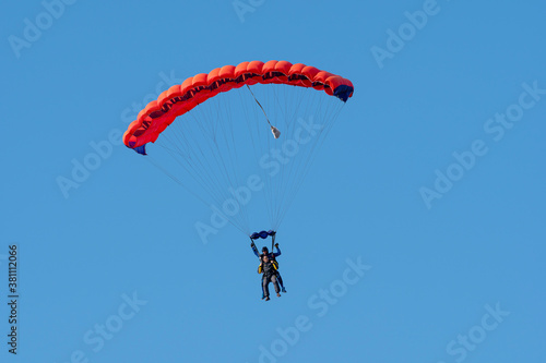 Tandem parachute jump. Silhouette of skydiver flying in blue clear sky. Concepts of extreme sport and adrenaline. 