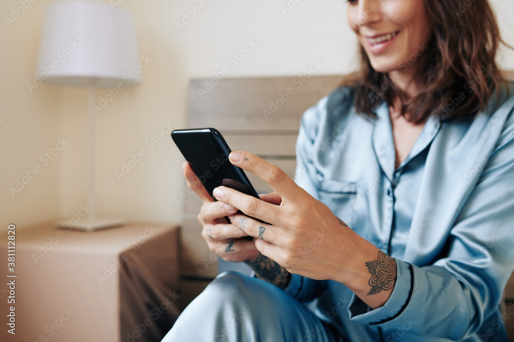 Close-up image of smiling young woman texting friends after getting up in the morning Close-up image of smiling young woman texting friends after getting up in the morning