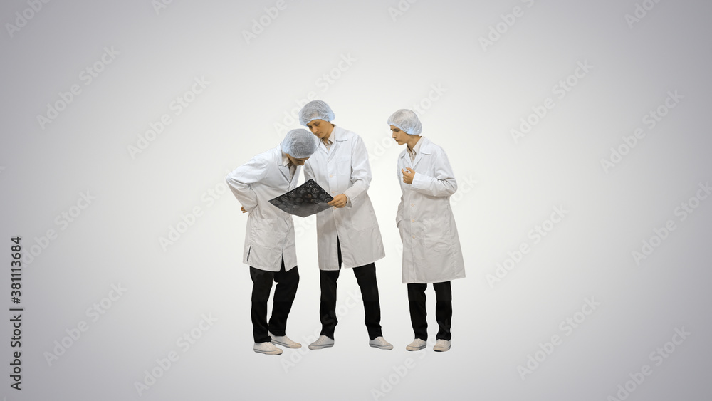 Three male doctors in white robes and protective caps looking at Three male doctors in white robes and protective caps looking at