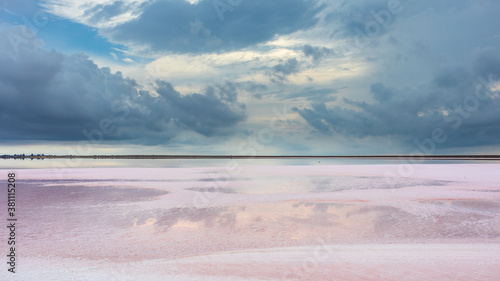 Salt pink lake reflective wet surface with gray high layered epic clouds on sky. Dramatic natural skyline on spa healthcare natural resort in Ukraine, Henichesk