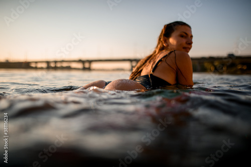 Close-up side view of woman lying on surf style wakeboard on water