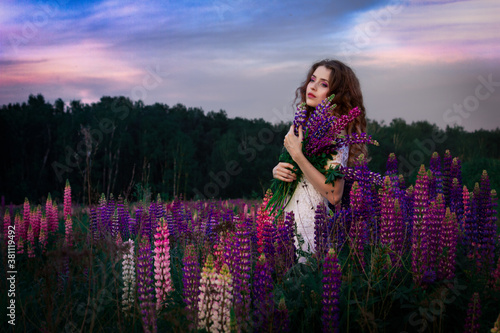 Fototapeta Naklejka Na Ścianę i Meble -  Beautiful, lovely girl among the flowers in the field. Lupins background. Nature and man.