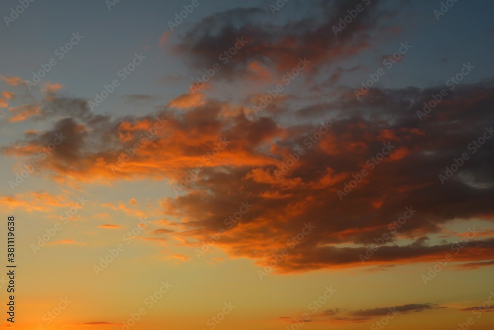 Beautiful fiery orange clouds in the sky at sunset, natural background
