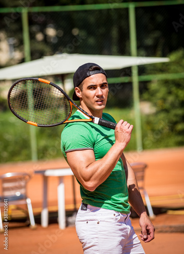 Portrait of young athletic man on tennis court.