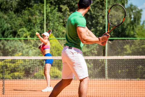 Young athletic couple playing tennis on the court. © romaset