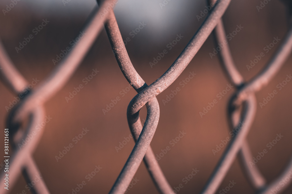 A close up of the links of a chain link fence using selective focus