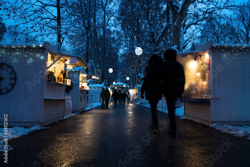 Advent market with foodstalls and lights with vistors in the night with snow in Zrinjevac Park in Zagreb in winter, Croatia photo