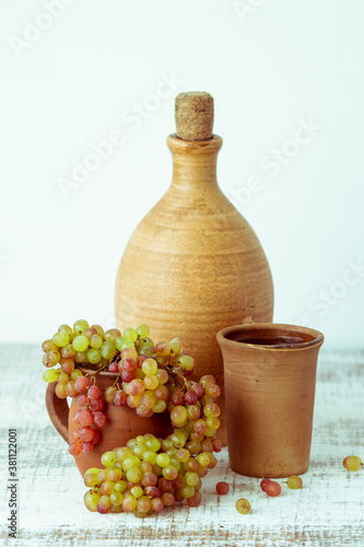 Homemade wine made from grapes in earthenware on an old wooden table. Selective focus. Tinted photo.