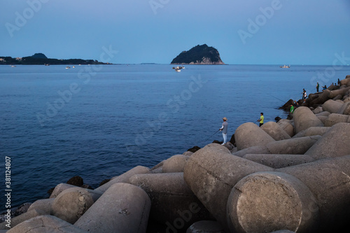 Fishermen on wave breakers after sunset at the harbour of Seogwipo, Jeju Island, South Korea