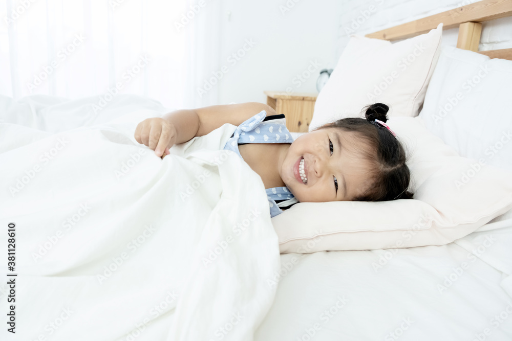 Adorable happy Asian toddler girl just wake up and still lie in bed with smiling face, happiness moment.. Adorable happy Asian toddler girl just wake up and still lie in bed with smiling face, happiness moment..