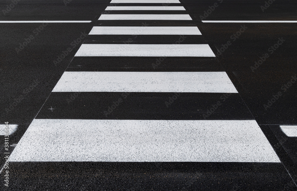 Front view of the pedestrian crossing, asphalt road, white stripes on a dark gray background, zebra stripes, perspective views, black and white, high temperature resistant draining asphalt. Front view of the pedestrian crossing, asphalt road, white stripes on a dark gray background, zebra stripes, perspective views, black and white, high temperature resistant draining asphalt.