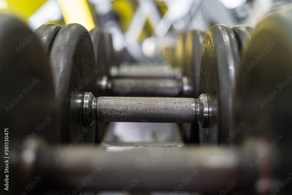 Close up on row of dumbbells in the rack in gym - selective focus background - dark image strength and fitness concept Close up on row of dumbbells in the rack in gym - selective focus background - dark image strength and fitness concept