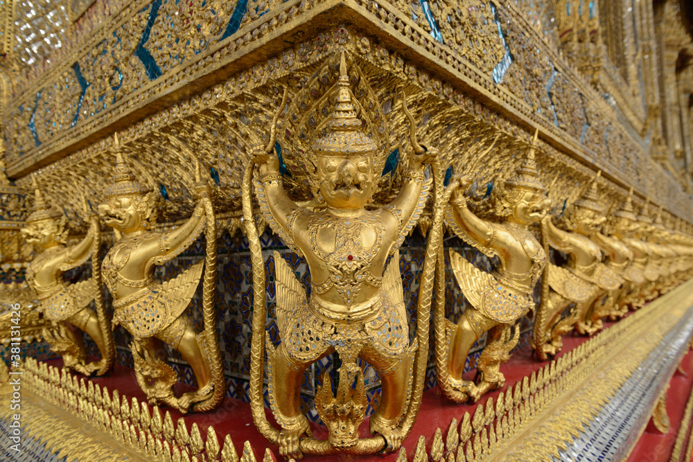 Selective focus on golden row of 112 Garudas at the central base of ordination hall, Wat Phra Kaew (Wat Phra Si Rattana Satsadaram), Bangkok, Thailand.