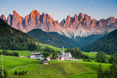 View of Val di Funes or Villnöß during sunset with Santa Magdalena church and Enrosadira or alpenglow effect on the Odle/Geisler massif, Val Gardena, Dolomites, South Tyrol, Italy