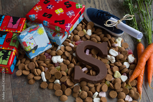 Dutch candy called Pepernoten eaten during Sinterklaas feast. Beside it presents for the kid and the shoe of the kid with carrots and a drawing