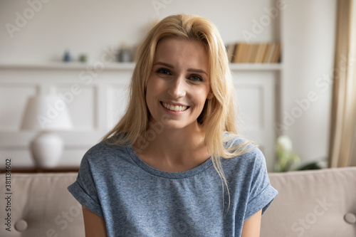 Portrait of smiling young female posing at home looking at camera while making videocall, recording vlog, passing distant job interview, providing internet consultation using webcam, profile picture