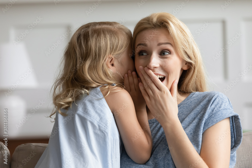 Do not tell anyone. Cute little kid daughter sharing secrets with trusted millennial mother, naughty preschool girl whispering funny gossip or joke on ear of amazed shocked laughing grown elder sister Do not tell anyone. Cute little kid daughter sharing secrets with trusted millennial mother, naughty preschool girl whispering funny gossip or joke on ear of amazed shocked laughing grown elder sister