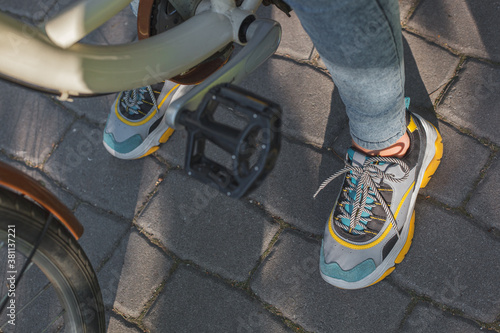 Feet shod in bright sneakers are next to the bicycle pedals