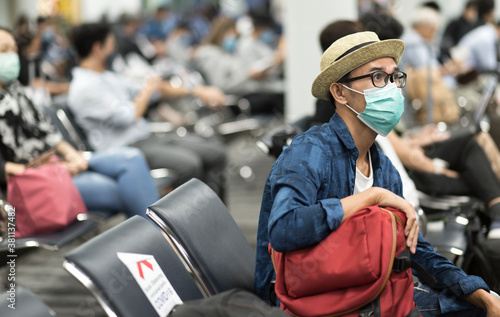 Tourist man with wearing medical mask sitting at gate and social distancing and waiting flight in Chiang Mai International Airport, Thailand. Travel New normal concept