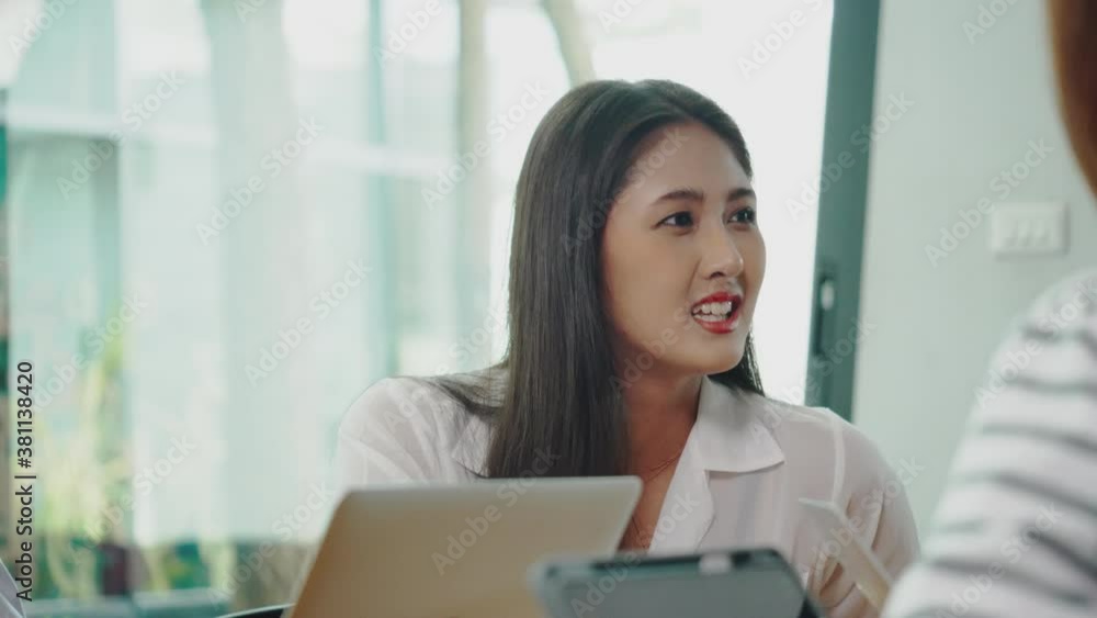Happy Asian woman is having a team meeting with her colleague in the office meeting room. Business women learn work plan And brainstorm with group of company. No social distancing or mask Happy Asian woman is having a team meeting with her colleague in the office meeting room. Business women learn work plan And brainstorm with group of company. No social distancing or mask