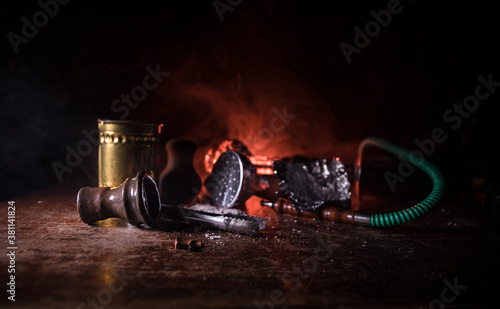 Hookah hot coals on shisha bowl making clouds of steam at Arabian interior. Shisha concept. Preparing shisha on table. Used shisha bowl on wooden table. Dark atmosphere with light. Selective focus. photo