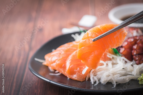Fresh Salmom sashimi on chopsticks with wood background,