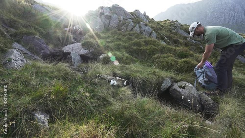 An outdoorsman getting drinking water from a mountain stream