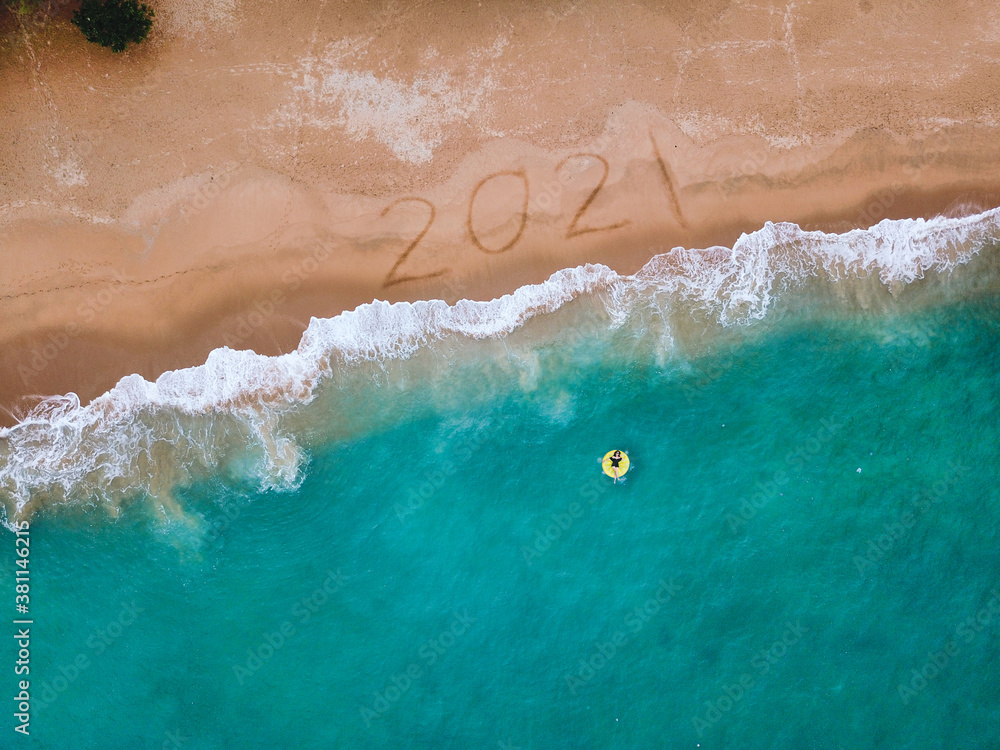 Happy New Year 2021, lettering on the beach with wave and blue sea. Numbers 2021 year on the sea shore, New Years concept.