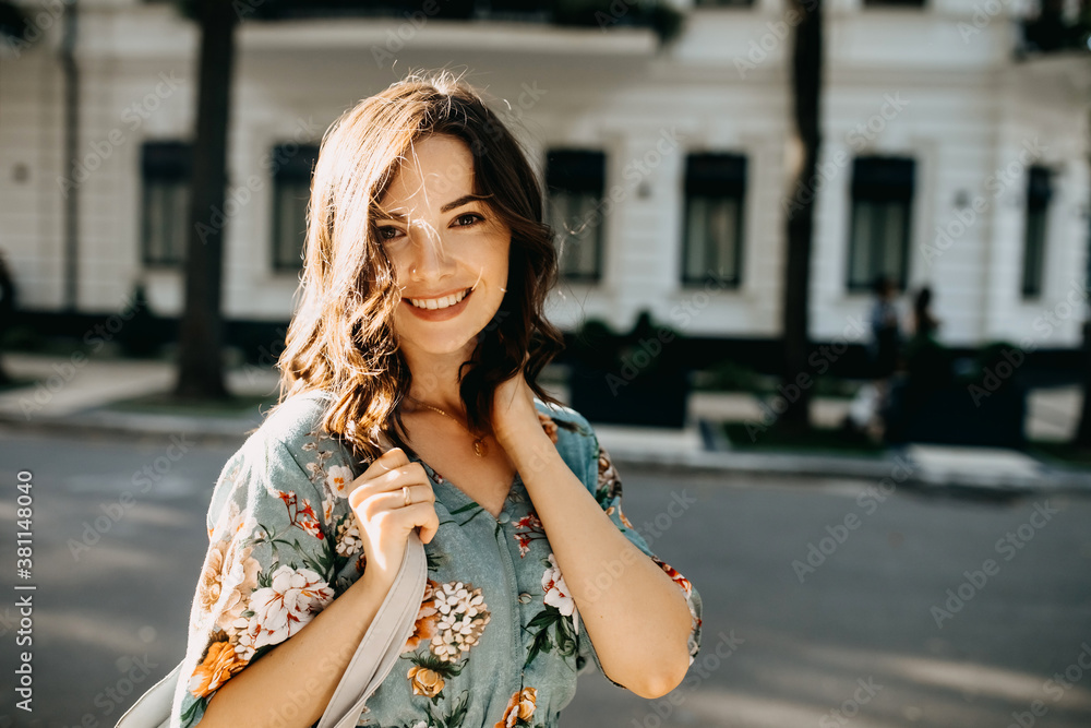 Young cheerful woman walking on city streets on summer day.