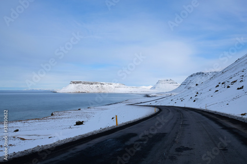 View from the road Snæfellsnesvegur driving along the coastline of the Snaefellsness Peninsula towards Kirkjufell Mountain in winter.